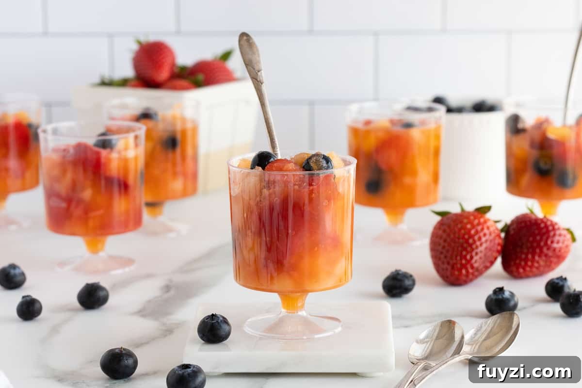Plastic cups filled with frozen fruit surrounded by blueberries and strawberries.