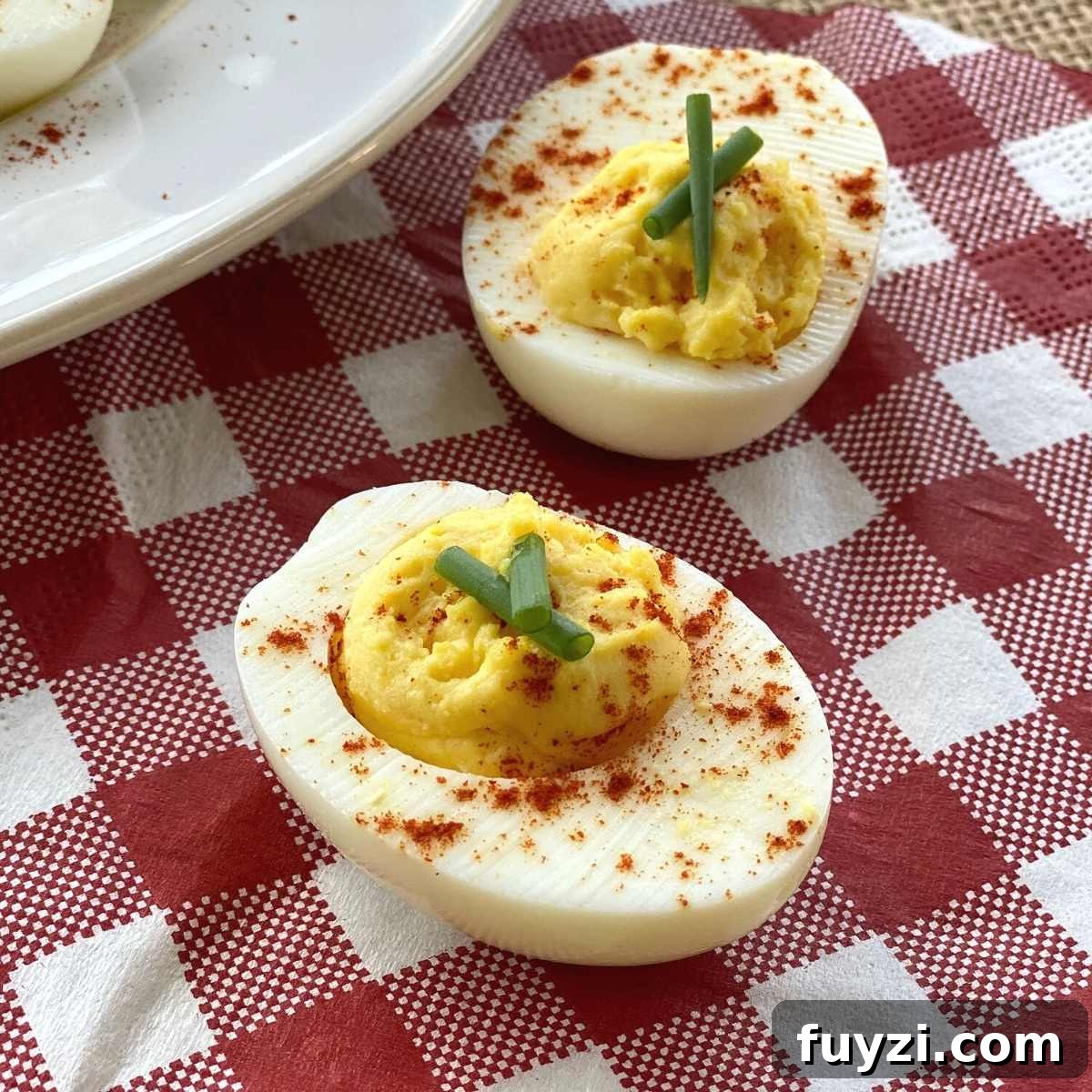 Two halves of low-carb deviled eggs on a red and white checkered napkin.