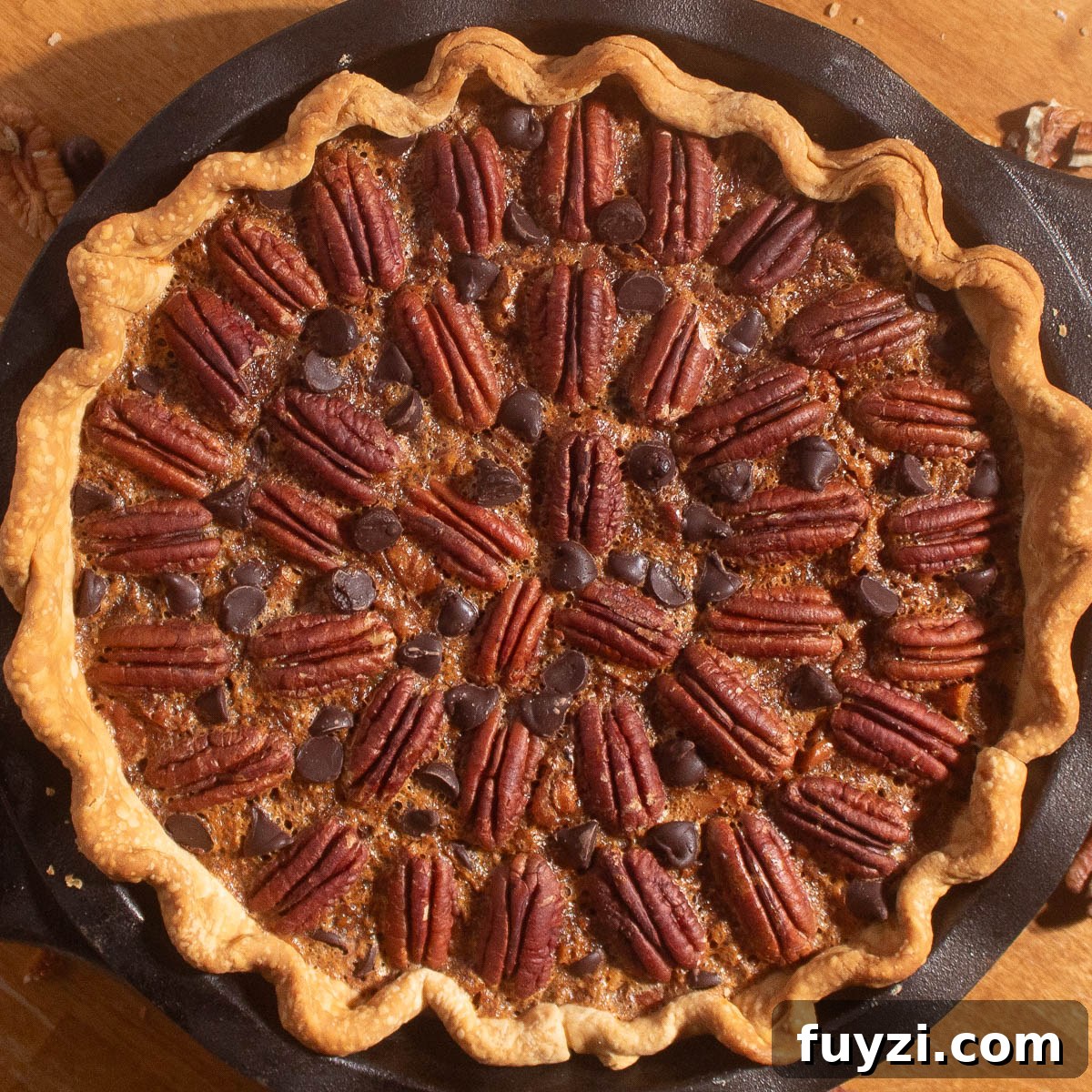 Golden chocolate chip pecan pie baked in a cast iron pan with pecans and chocolate chips on top.