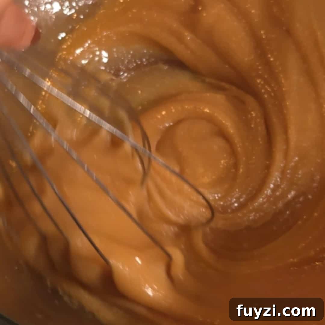 Whisking together brown sugar, butter, and corn syrup to create the smooth filling for chocolate chip pecan pie.