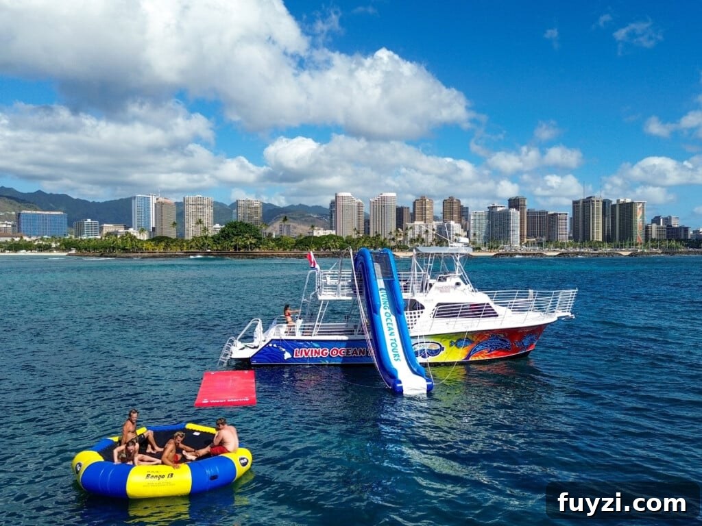 A recreational boat with waterslide and floating platform anchored off Waikīkī with city skyline and greenery in the background.