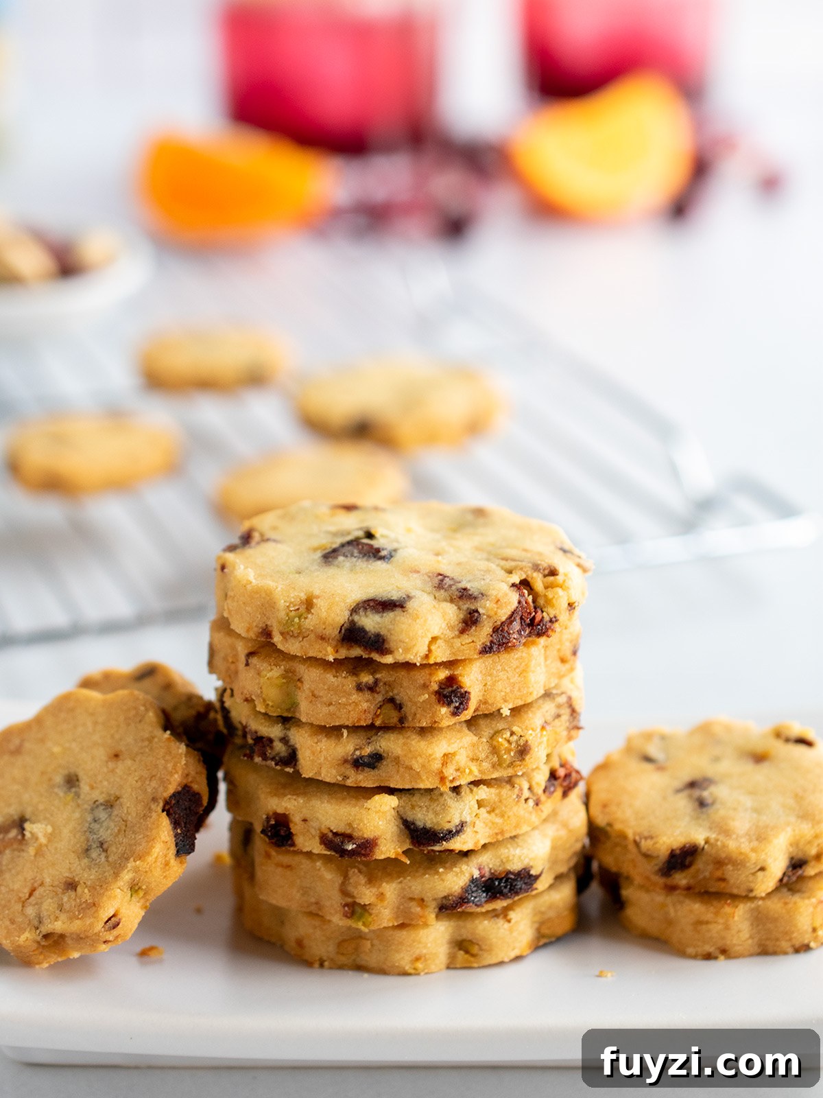 Stacked cookies on white plate with cooling rack on the left in the background plus two cocktails.