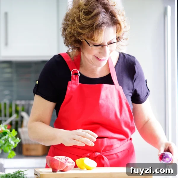 Beth Lee in red apron looking at vegetables on cutting board