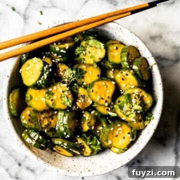 Korean cucumber salad in a ceramic bowl with sesame seeds and wooden chopsticks