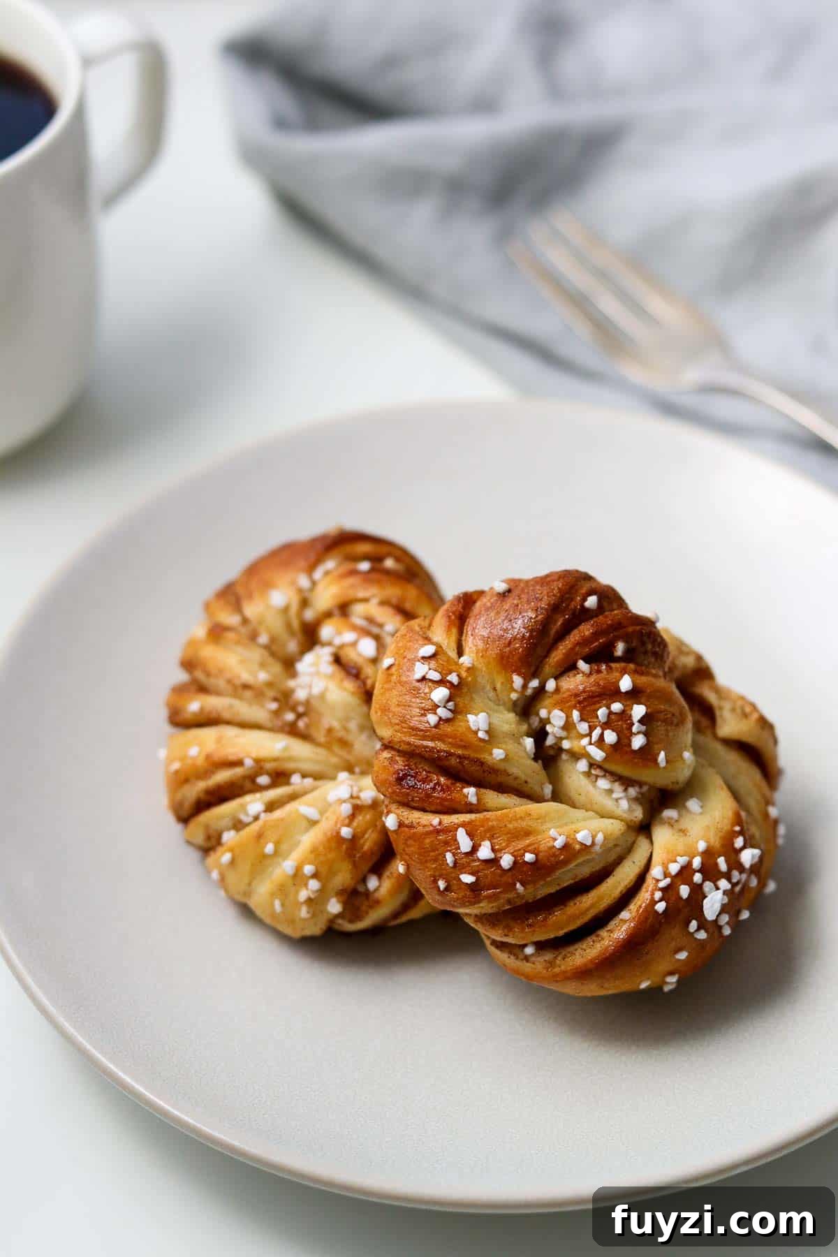 Swedish Cinnamon Buns (Kanelbullar) on a plate next to a fork and coffee.