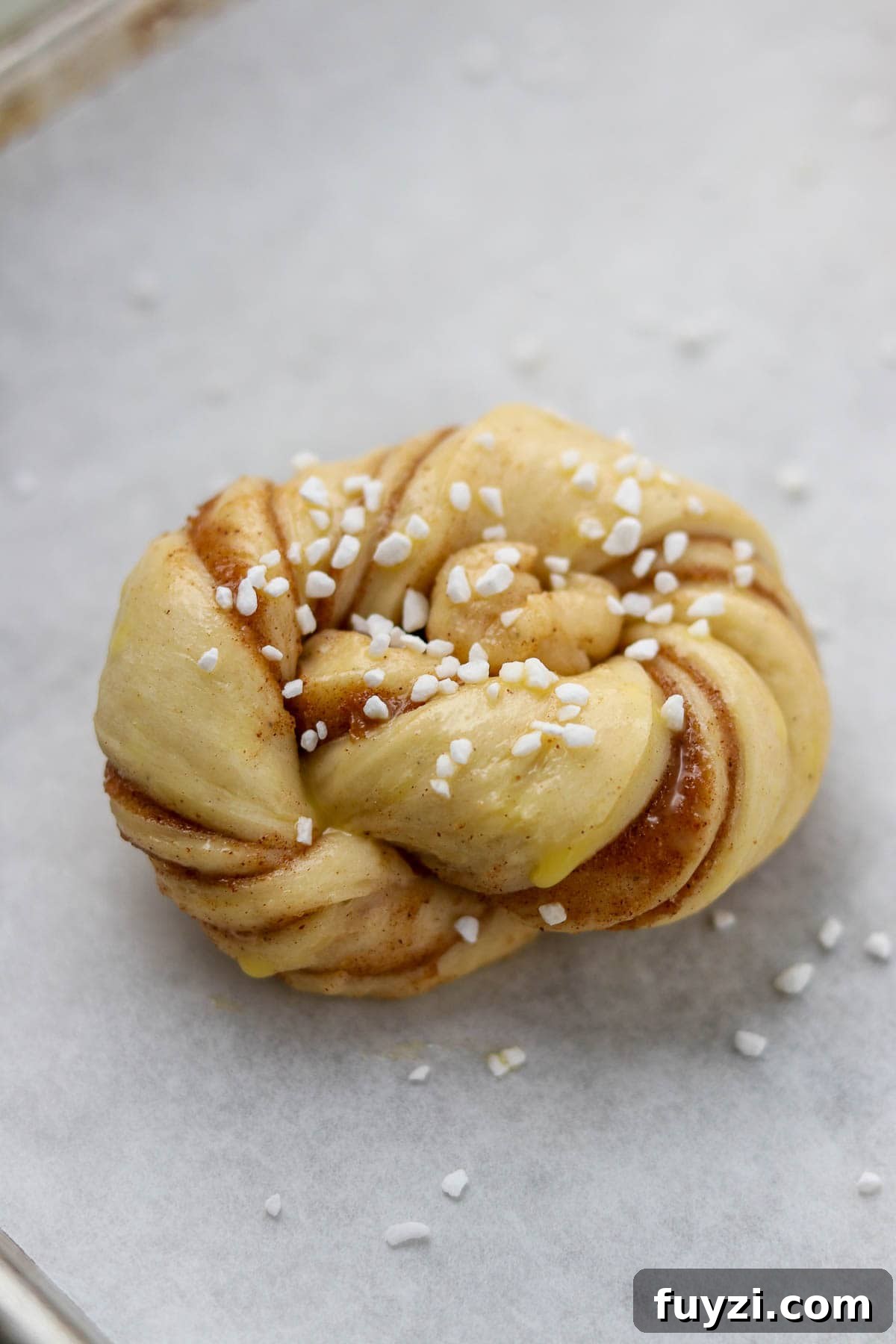 Unbaked Swedish Cinnamon Bun (Kanelbullar) sprinkled with pearl sugar.