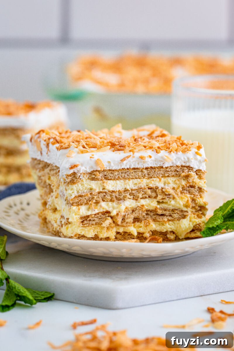 a slice of coconut icebox cake on a small plate with a sprig of mint