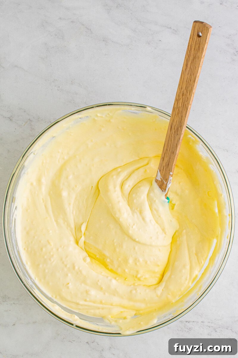 coconut cream pudding and cool whip folded together in a mixing bowl