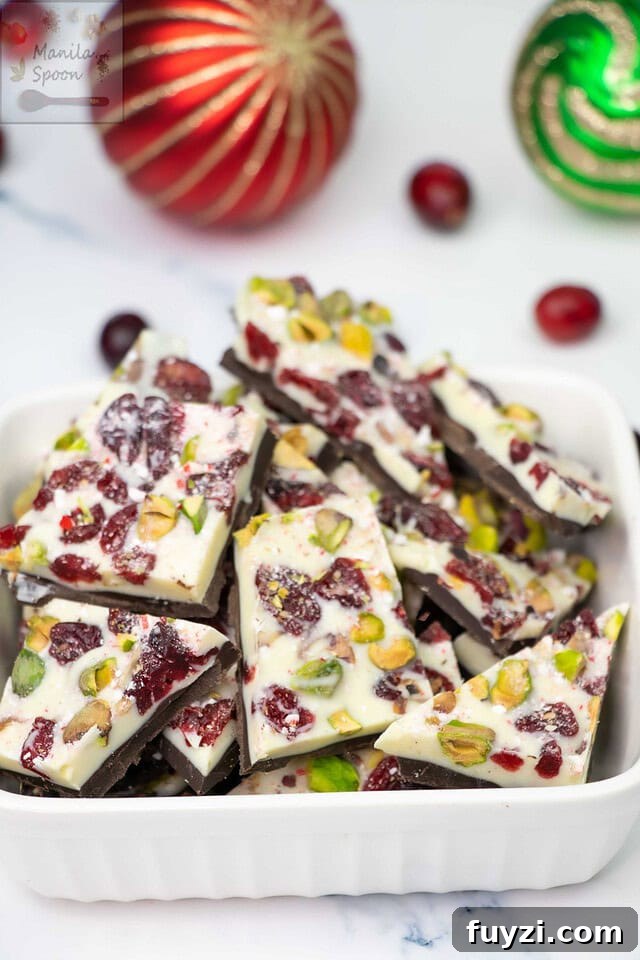 With a layer of dark and white chocolate and dotted all over with red cranberries and green pistachios, this gorgeous double chocolate bark is the ultimate holiday candy! So easy to make and the taste is simply outstanding! Make the holidays special with this Easy Double Chocolate Bark with Cranberries and Pistachios! Featuring layers of rich dark and creamy white chocolate topped with festive red cranberries and green pistachios, this quick and stunning candy is as delicious as it is beautiful!