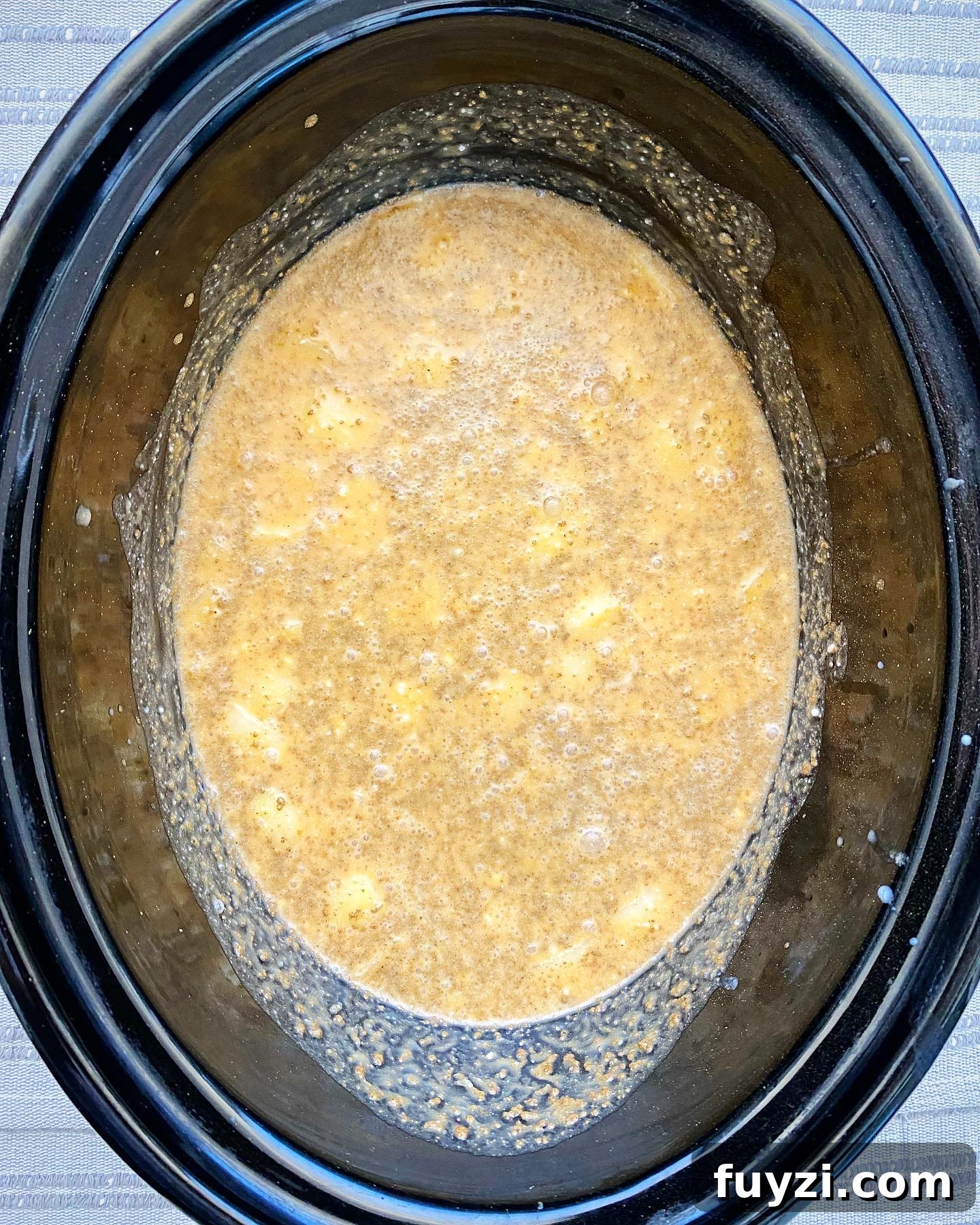 Creamy Slow Cooker Pumpkin Bisque 4 overhead shot of uncooked crockpot pumpkin bisque in a black slow cooker