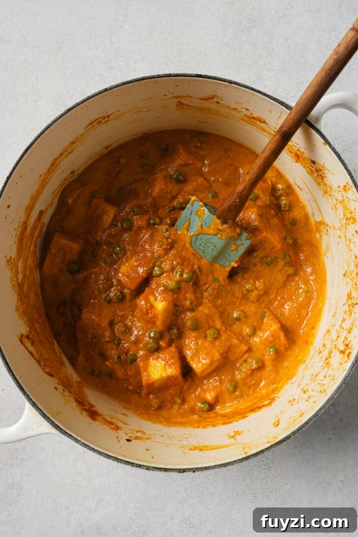 Authentic Restaurant-Style Matar Paneer Recipe 16 Matar Paneer in a dutch oven with a rubber spatula.