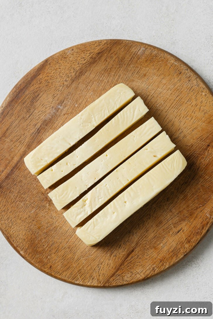 Authentic Restaurant-Style Matar Paneer Recipe 6 Paneer cut into 1/2" vertical strips on a wooden cutting board.