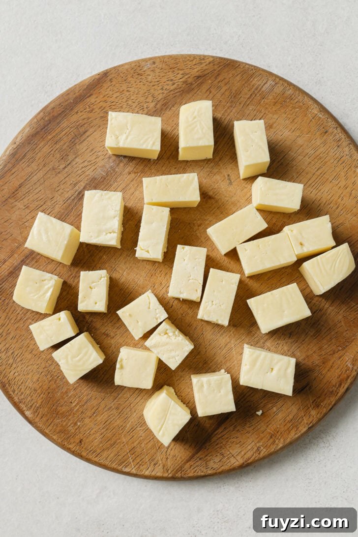 Authentic Restaurant-Style Matar Paneer Recipe 7 Cubed paneer on a wooden cutting board.
