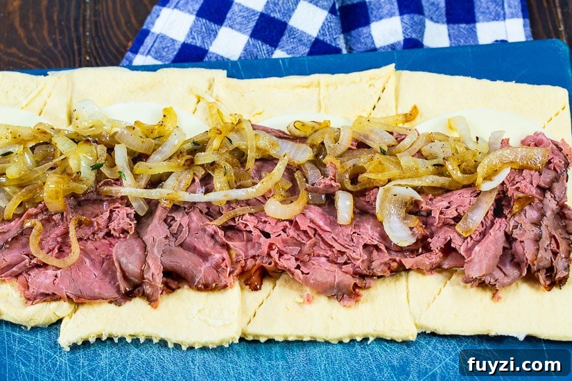 French Dip Pinwheels Recipe: Party Appetizer with Au Jus 4 Roast beef and onions spread out on crescent roll dough.