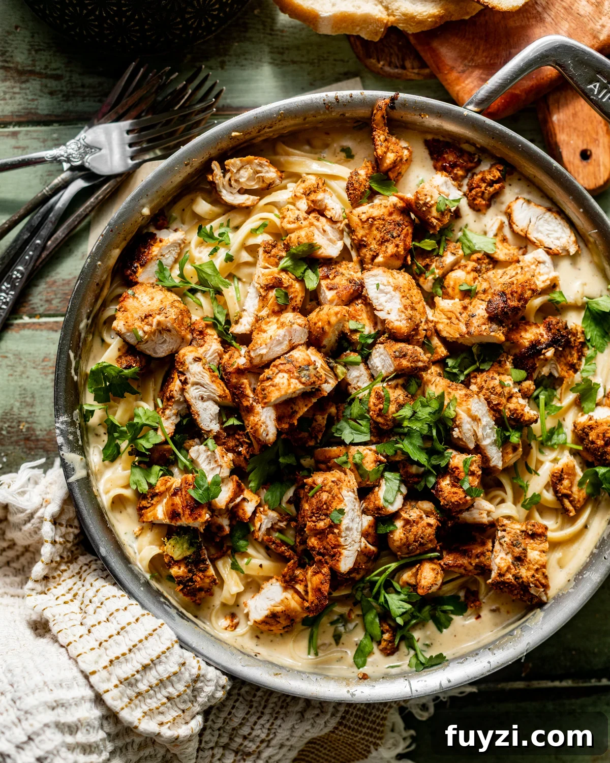 finished blackened chicken alfredo in a skillet with blackened chicken cut into pieces and placed on top of the pasta.
