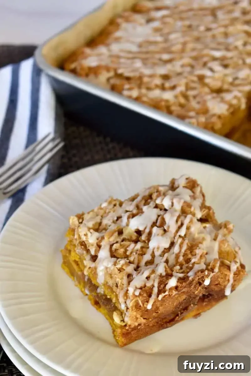 Pumpkin Streusel Coffee Cake Recipe with Cinnamon Crumble 2 Pumpkin Streusel Coffee Cake on a plate with a pan of cake in the background.