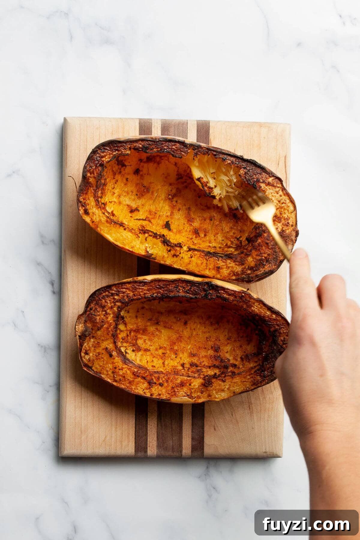 Cooked spaghetti squash being fluffed with a fork to create low-carb noodles.