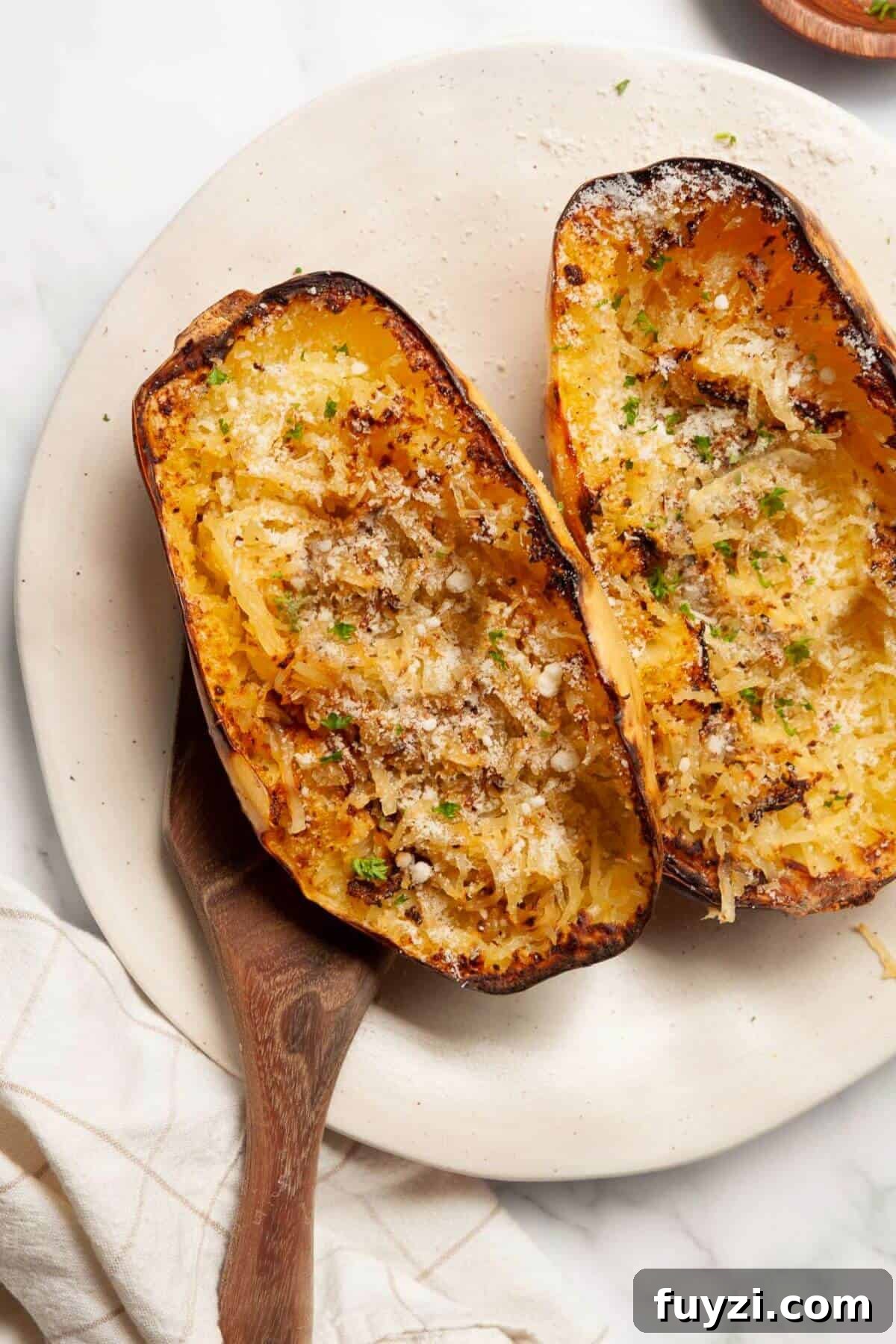 Golden, tender air fryer spaghetti squash halves with parmesan cheese and parsley.