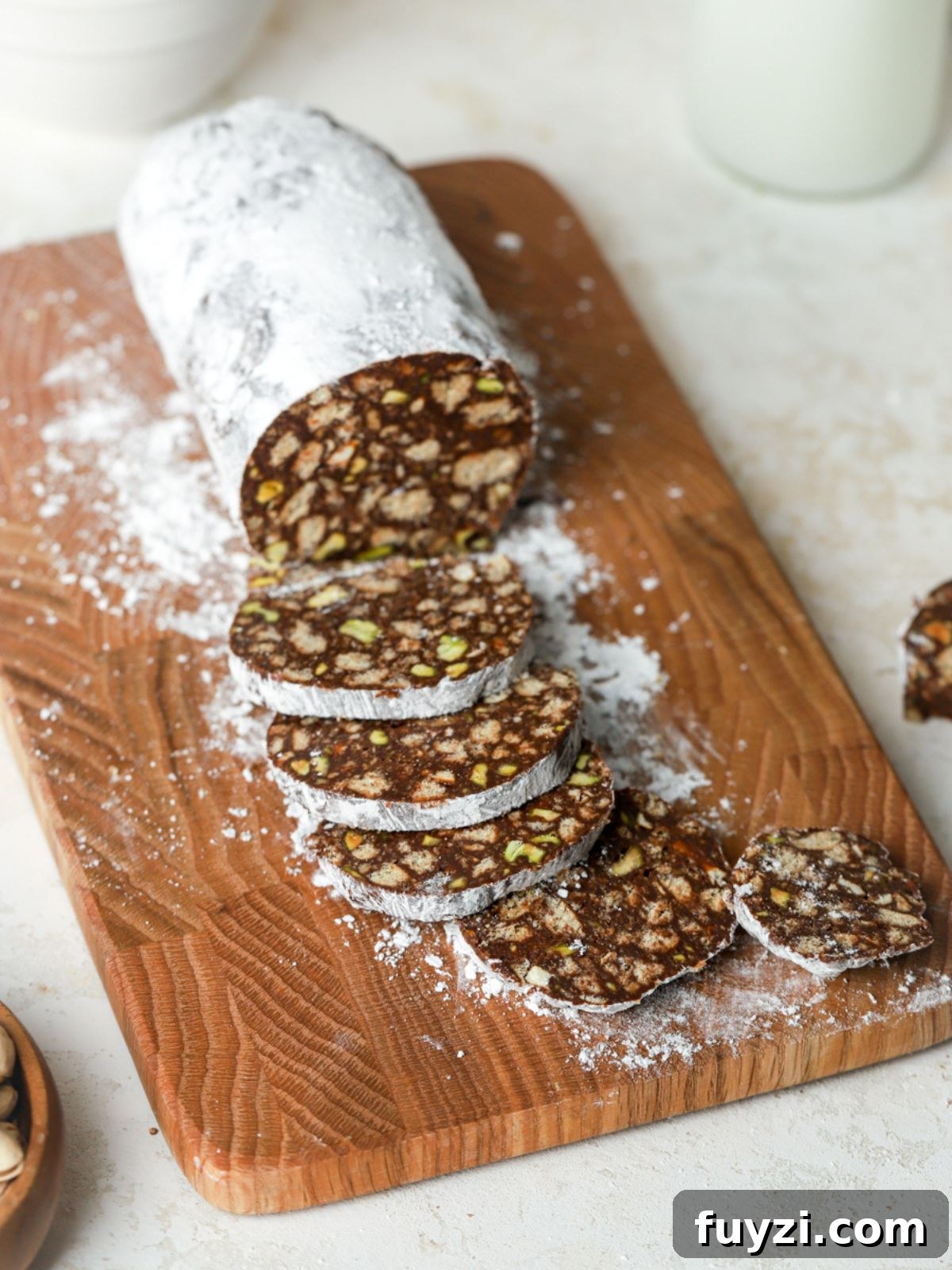 A log of chocolate coated with powdered sugar being sliced on a cutting board