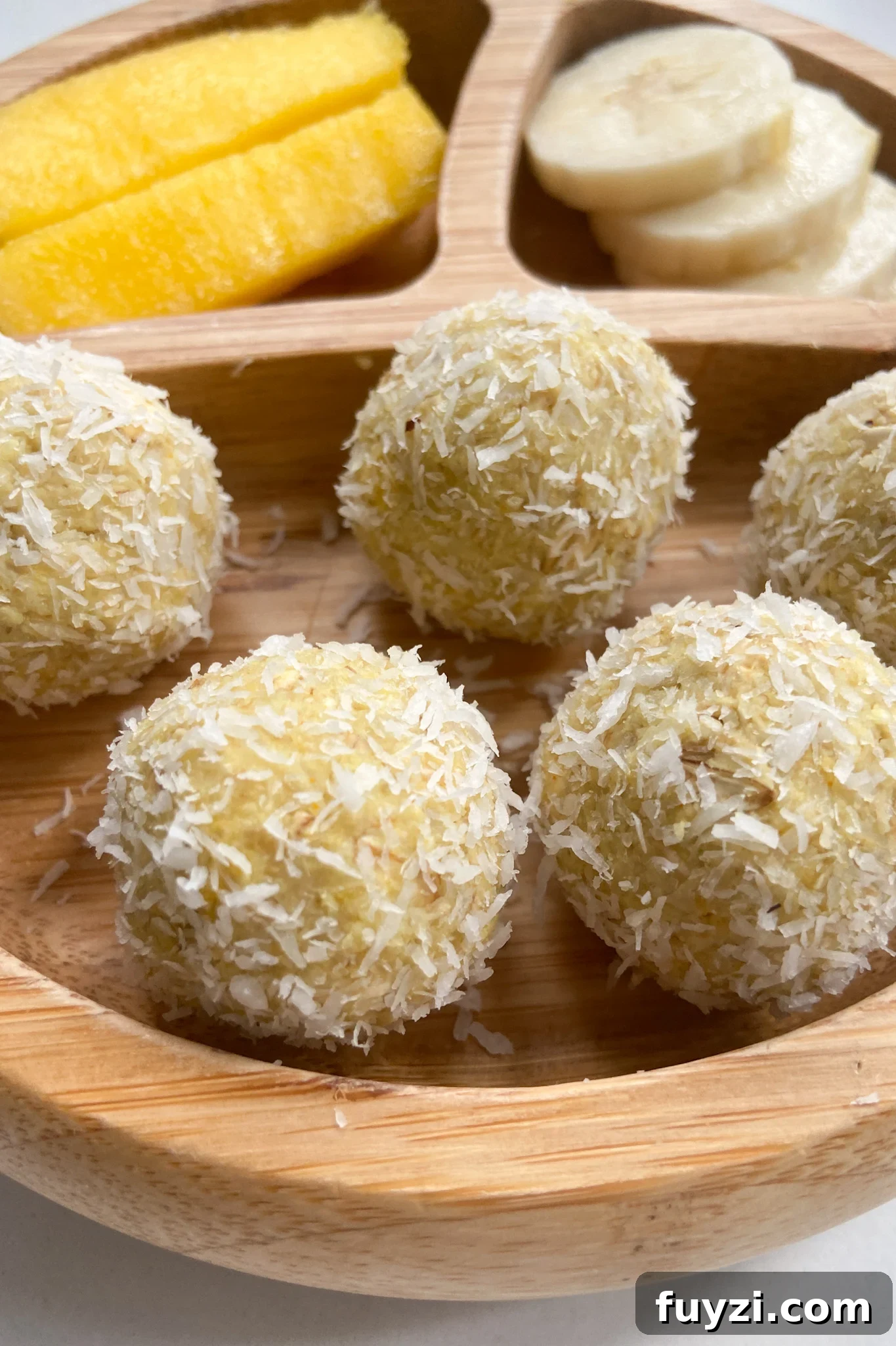 Mango bliss balls served with sliced mangoes and bananas