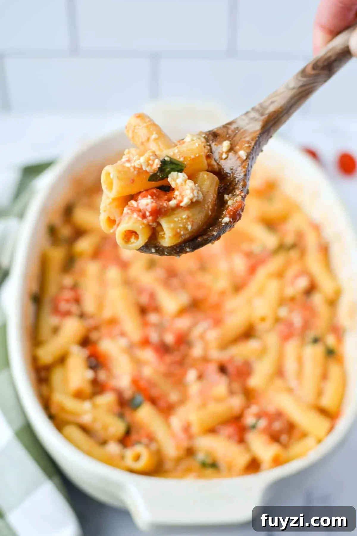 A baking dish of pasta, with a spoon taking a portion.