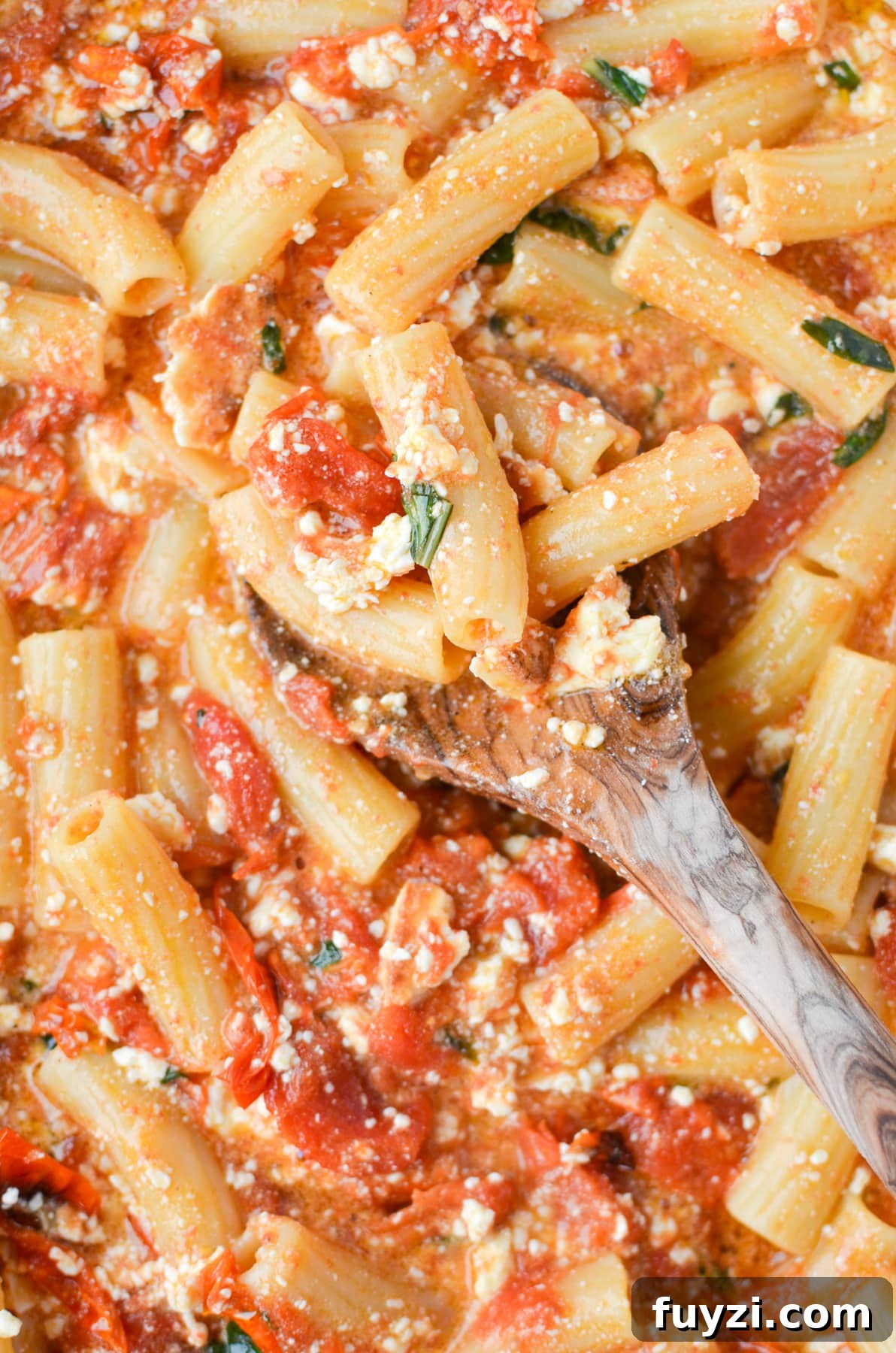 Spooning pasta with a wooden spoon.