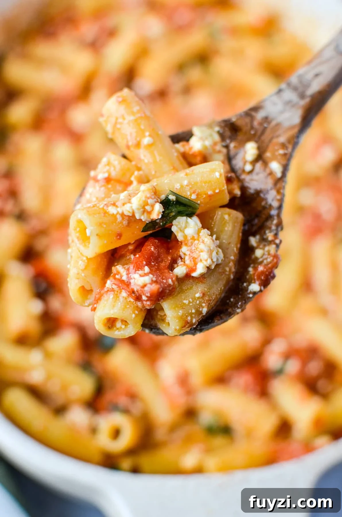A spoonful of cooked pasta with tomatoes and feta.