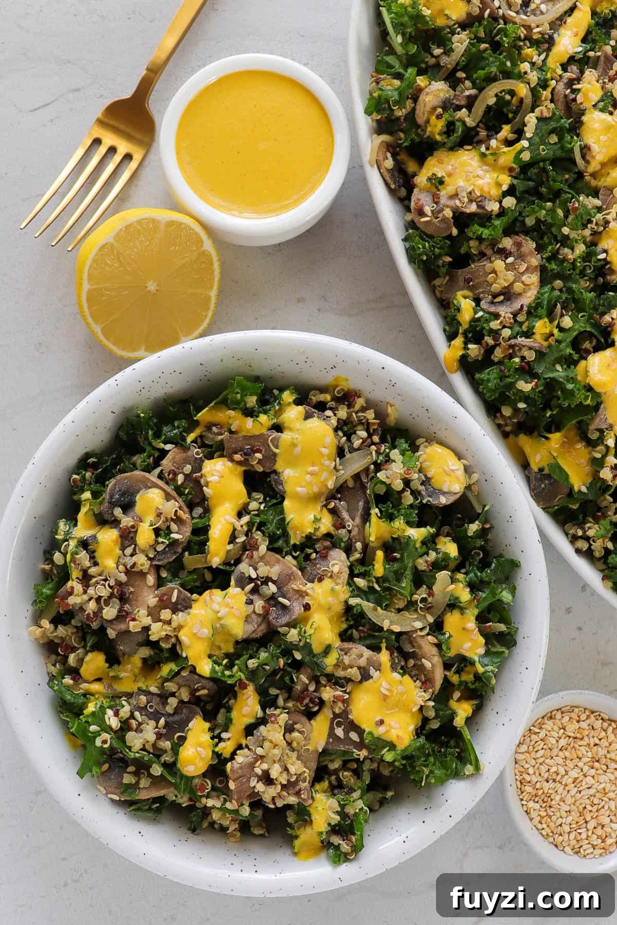 Warm Cheesy Quinoa Salad with Kale and Sauteed Mushrooms 7 Salad served in a bowl with cut lemon, sesame seeds and extra dressing on the side.