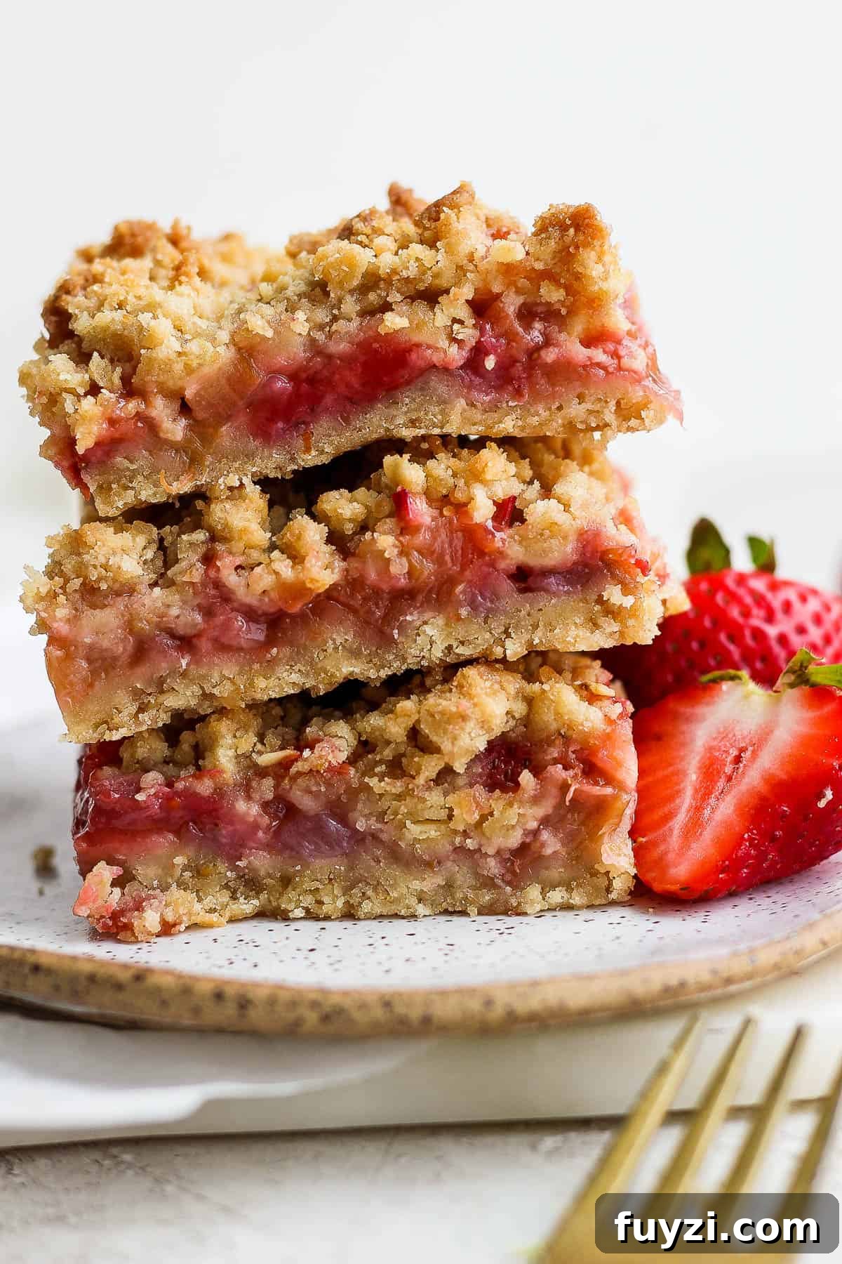 Three bars stacked on top of each other on a plate with fresh strawberries next to them.