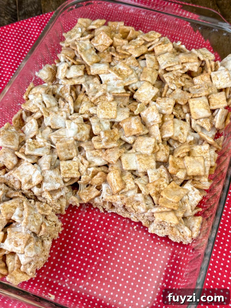 Copycat Cinnamon Toast Crunch Cereal Bars Recipe 7 Overhead view of a 9 x 13 pan of cereal bars with a section cut out on a red and white napkin.