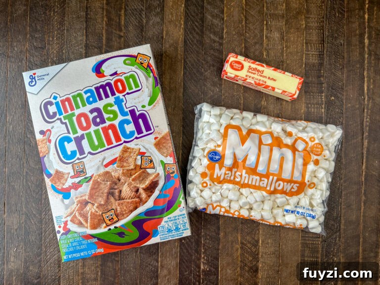Copycat Cinnamon Toast Crunch Cereal Bars Recipe 4 Ingredients to make cereal bars are cinnamon toast crunch, butter and mini marshmallows on a wooden counter top.