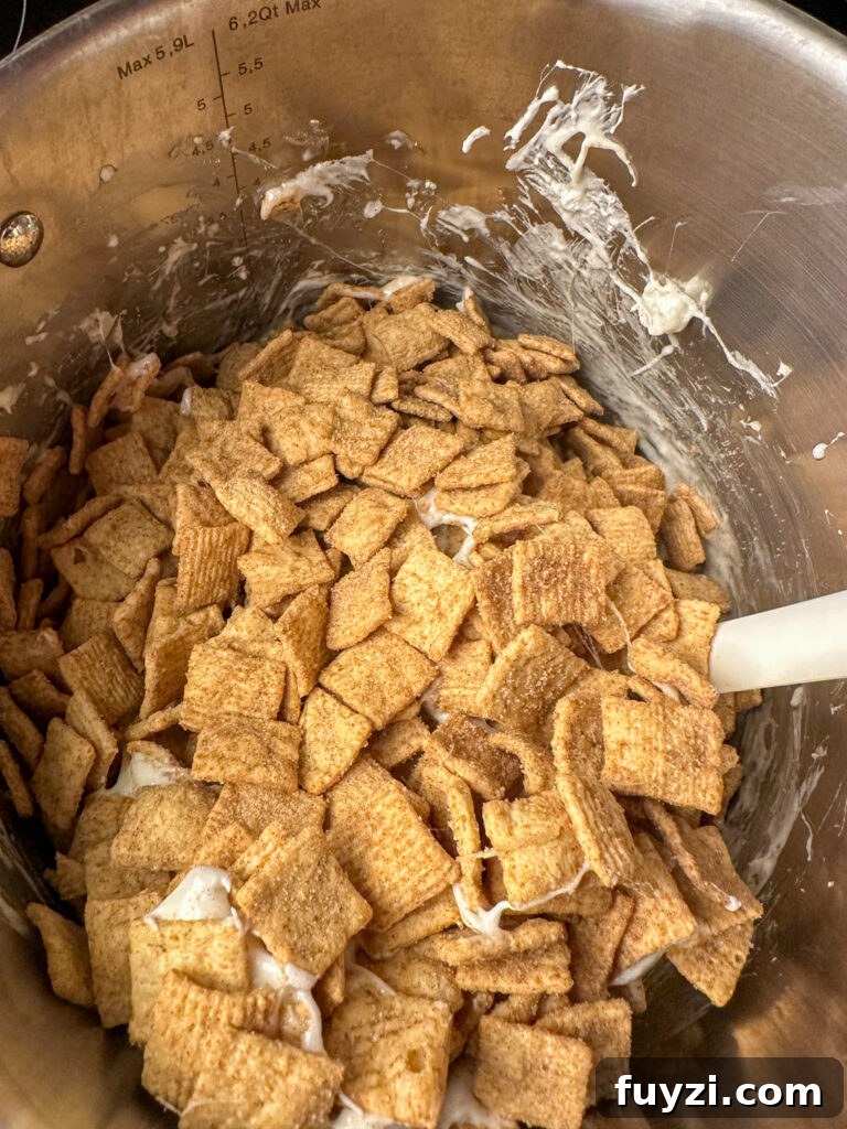 Copycat Cinnamon Toast Crunch Cereal Bars Recipe 5 Spatula stirring cinnamon toast crunch into melted marshmallows and butter to make a cereal bars recipe.