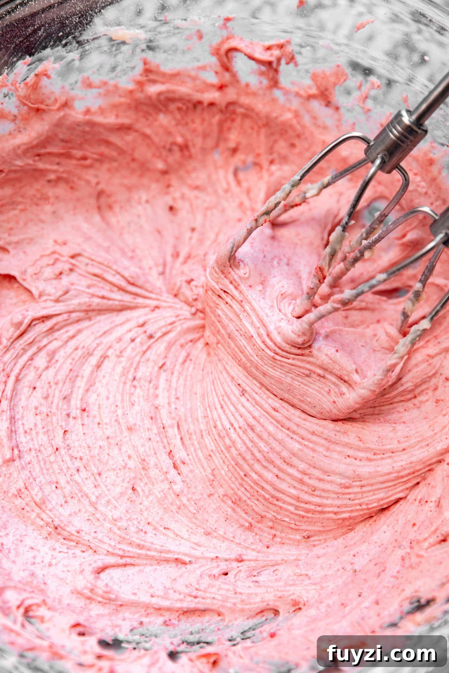 Freeze-dried strawberry powder being beaten into cream cheese frosting.