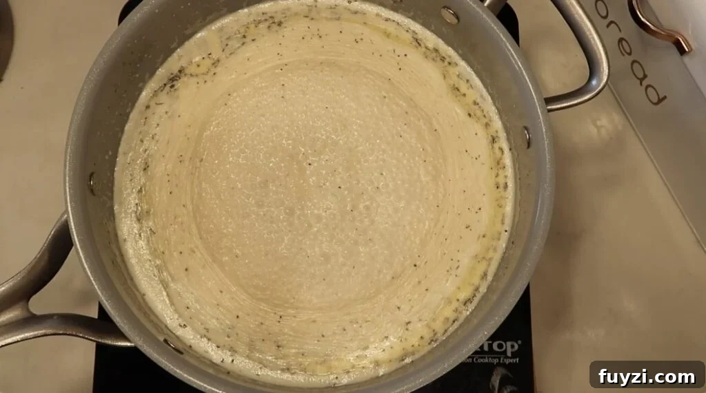 Silky Garlic Cream Sauce Recipe for Pasta and Chicken 13 Sauce simmering and thickening in pan