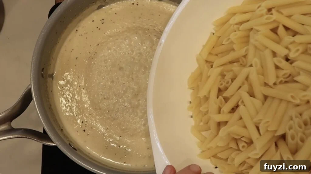 Silky Garlic Cream Sauce Recipe for Pasta and Chicken 15 Adding pasta to pan with sauce in it