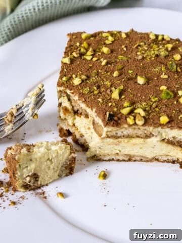 Pistachio Cream tiramisu on a plate with a forkful scooped out.