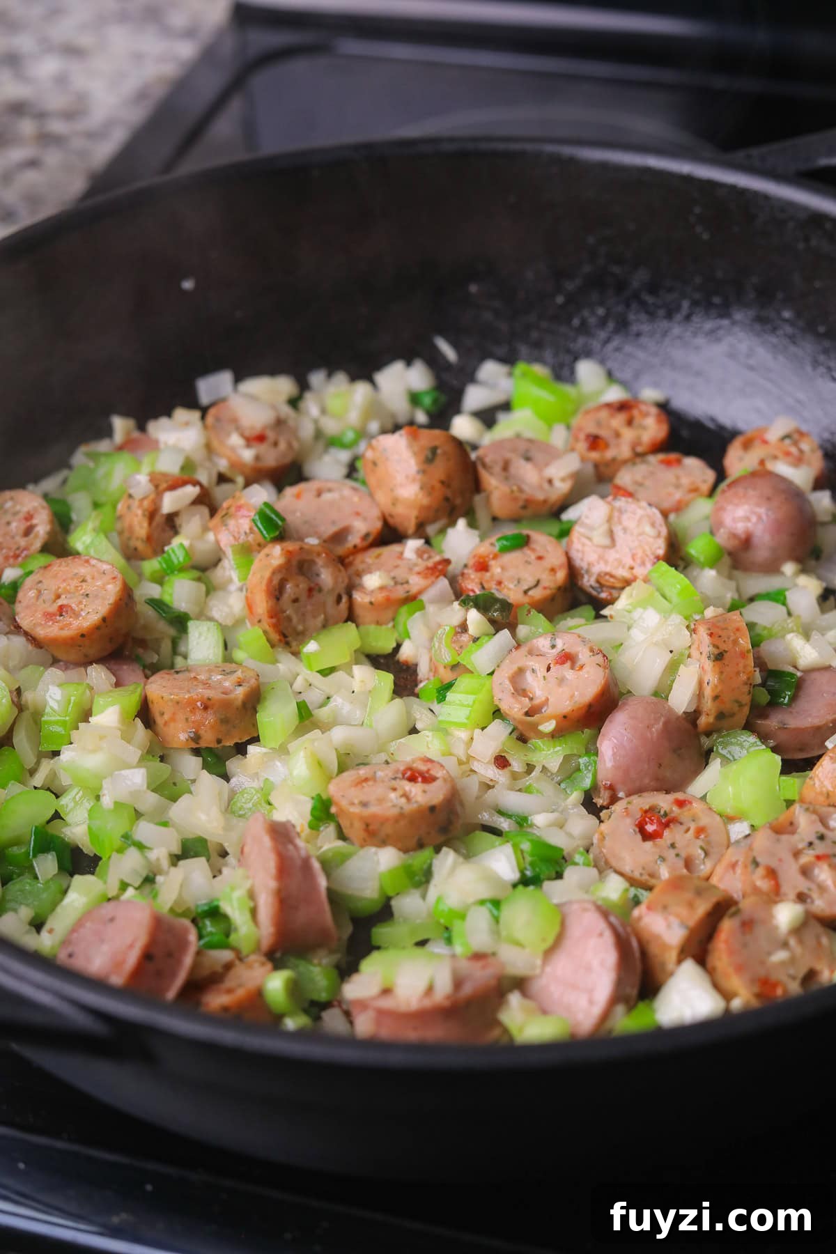 Sausage and chopped veggies cooking in a skillet