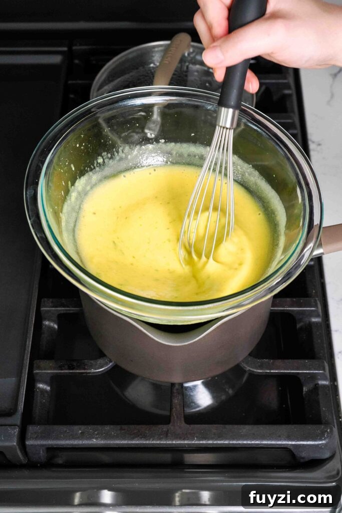 Mango curd is whisked over a bain-marie on the stove.