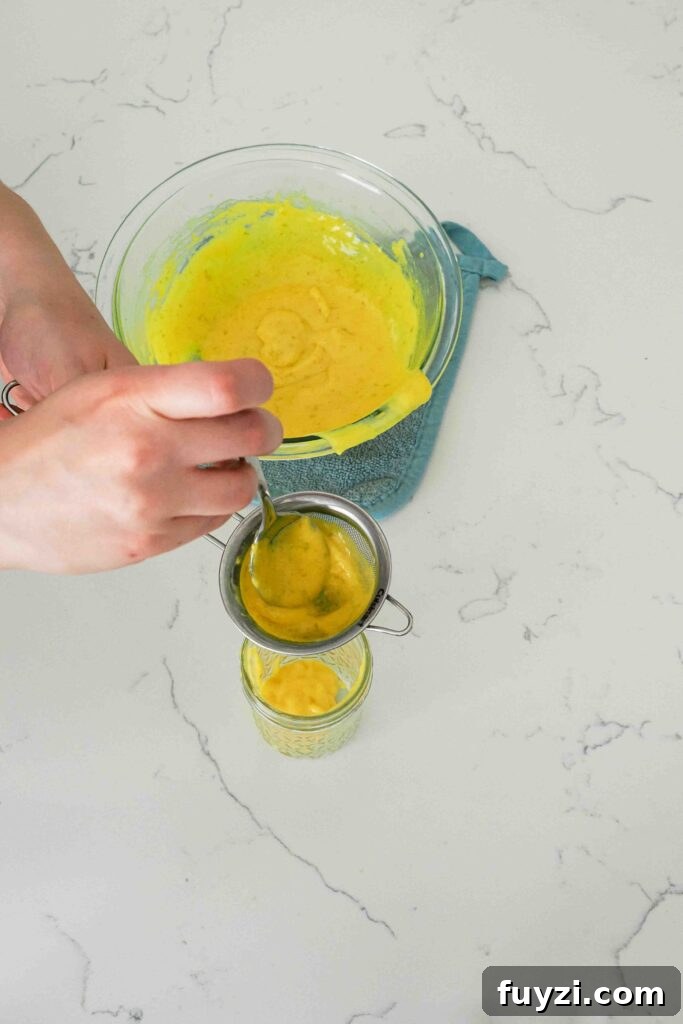 Mango curd is passed through a fine mesh strainer to remove the lime zest.