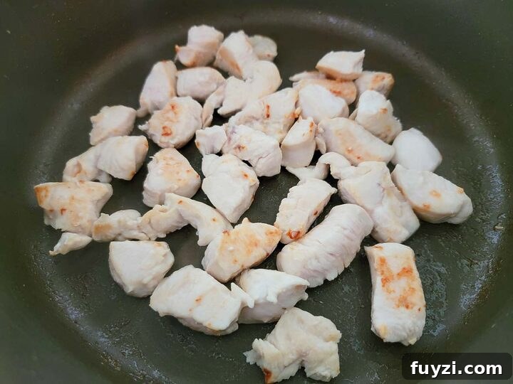 Creamy Chicken Noodle Casserole with Golden Crust 3 diced chicken cooking in a frying pan.