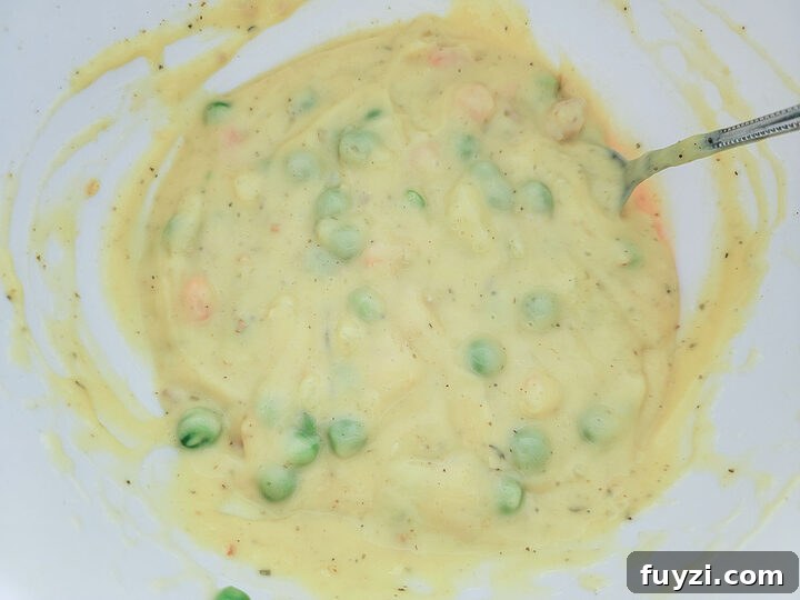 Creamy Chicken Noodle Casserole with Golden Crust 4 chicken, peas, carrots, and creamy sauce in a bowl.