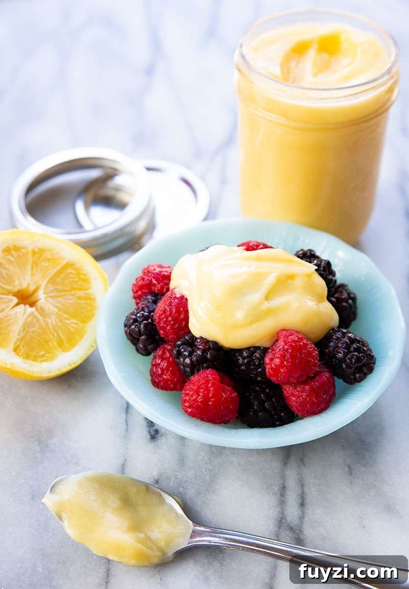 Close up shot of the sugar free lemon curd in a bowl and a jarred batch in the background.