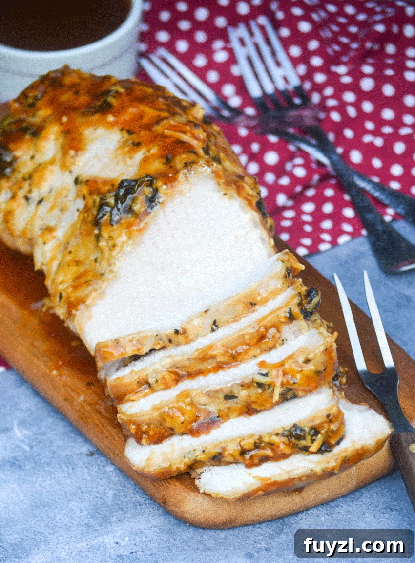 a meat fork stuck in slices of honey garlic pork tenderloin on a wooden cutting board