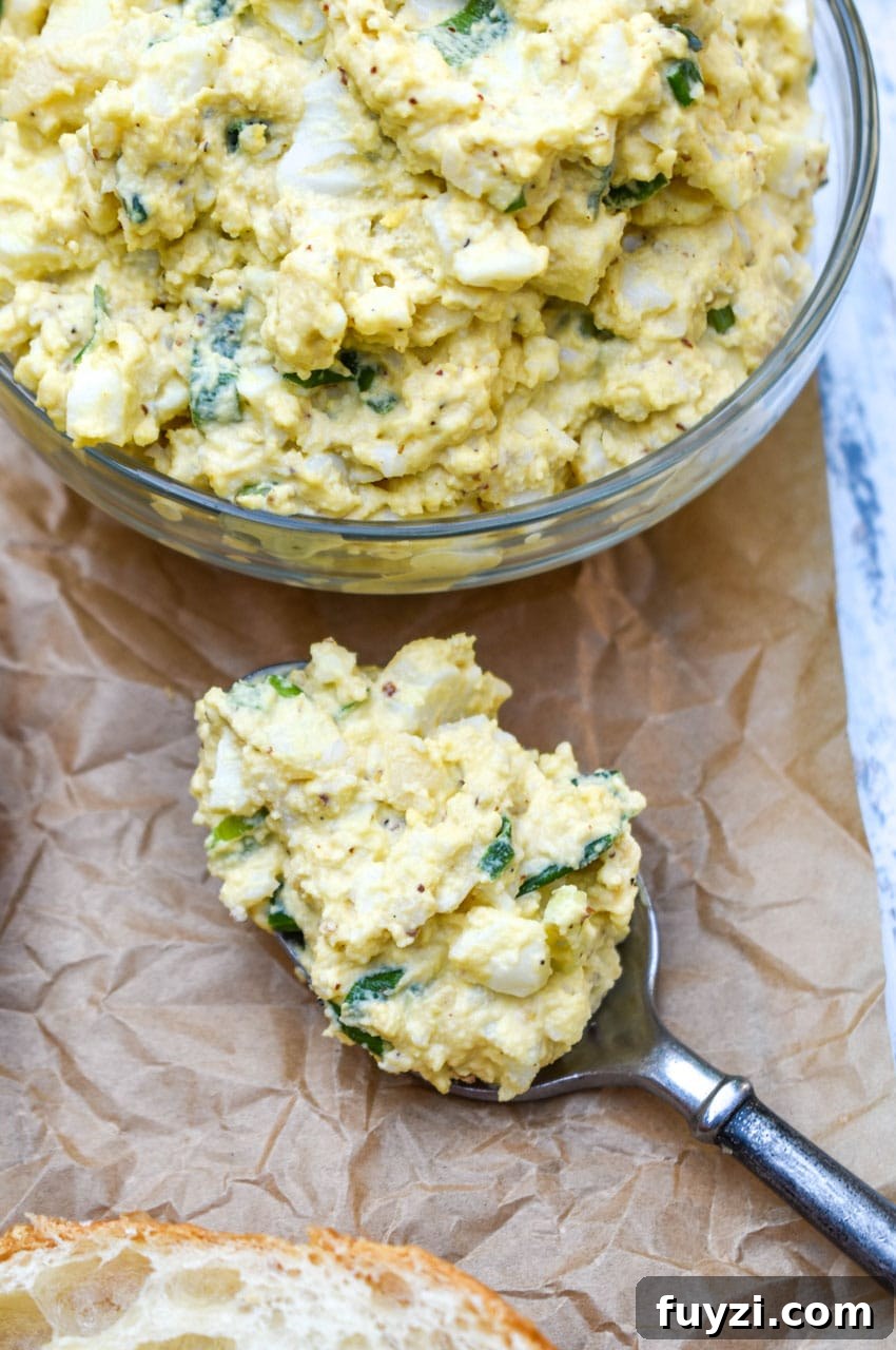 Smoked Egg Salad Recipe for Sandwiches and Salads 7 a spoon holding a scoop of smoked egg salad resting on crinkled brown parchment paper