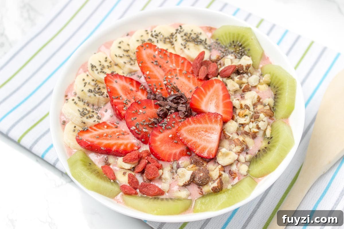 Strawberry Ginger Smoothie Bowl with toppings - kiwi, banana, seeds.