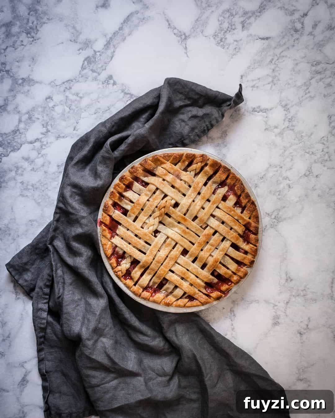 Marble surface with baked lattice pie with a grey linen towel nearby