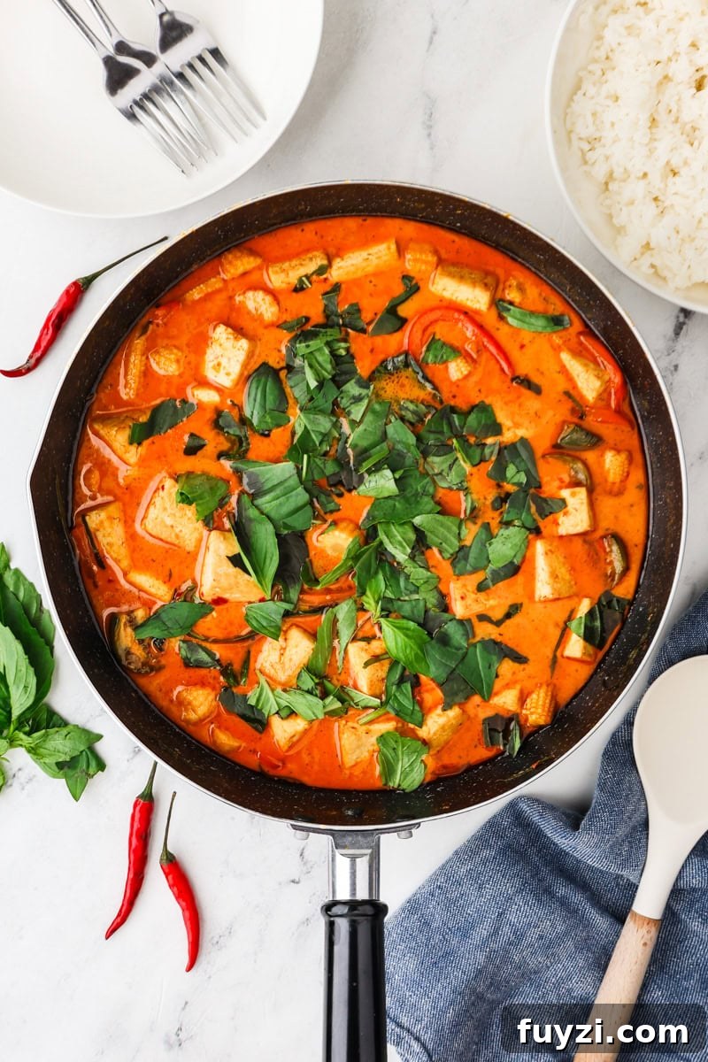 An overhead image of adding the thai basil leaves as garnish.