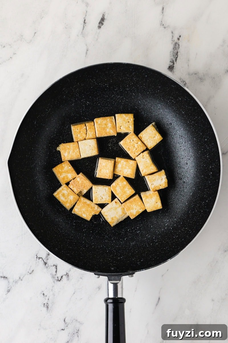 An overhead image of frying tofu on a skillet.