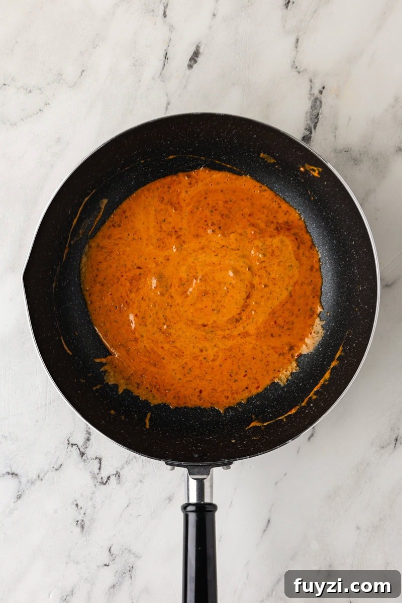 An overhead image of combining the thick part of coconut milk with red curry paste.