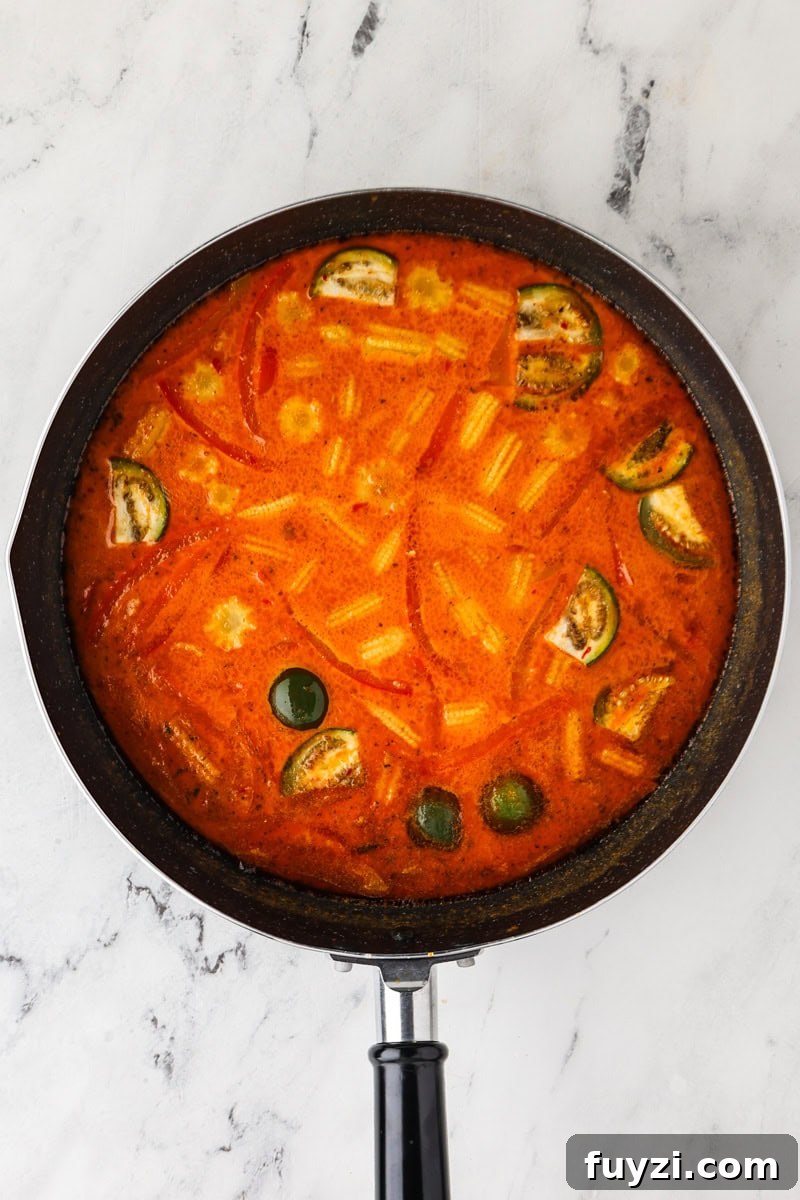 An overhead image of adding the eggplants, red bell pepper, and baby corn.